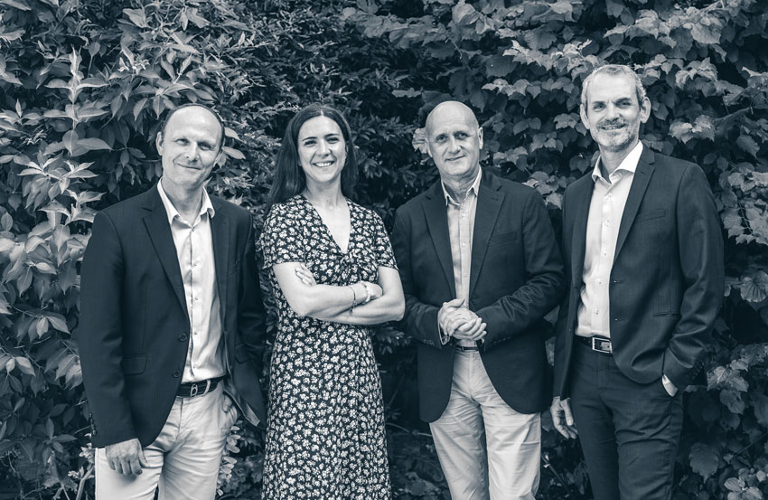 3 hommes et une femme posent dans un jardin, en bichromie bleue